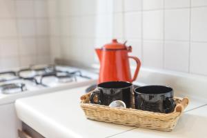 a basket with three coffee mugs on a kitchen counter at Homy Apartments Altaguardia in Milan