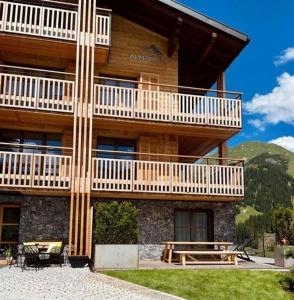 um grande edifício de madeira com uma varanda e uma mesa de piquenique em Boutique Chalet Almrausch em Lech am Arlberg