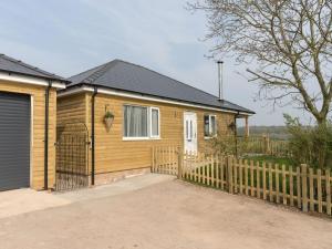 a wooden house with a fence in front of it at The Old Kennels in Tibberton