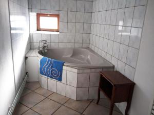 eine Badewanne im gefliesten Bad mit einem Tisch in der Unterkunft Le Bourdon bleu à Celles en Bassigny in Celles-en-Bassigny