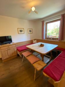 a living room with a table and benches and a television at Ferienhaus Islitzer in Hollersbach im Pinzgau