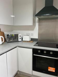 a kitchen with a black oven and a microwave at Lovely 2 Bedroom Serviced Apartment with Parking in West Bromwich