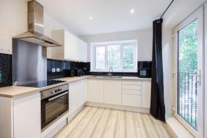una cocina con armarios blancos y fregadero en Modern apartment -Perfect for Contractors & Families By Luxiety Stays Serviced Accommodation Southend on Sea en Southend-on-Sea