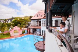eine Frau und ein Kind auf einem Balkon mit Poolblick in der Unterkunft The Pool Resort OKINAWA in Onna