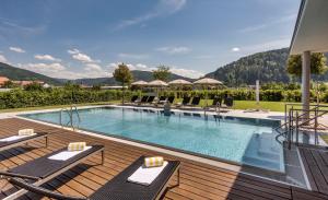 a swimming pool on a deck with lounge chairs next to it at Mosers Blume Relax & Genuss Hotel in Haslach im Kinzigtal