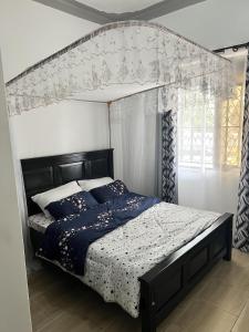 1 dormitorio con cama con dosel y ventana en Spacious and comfortable House in Kampala Uganda en Kasiyirize