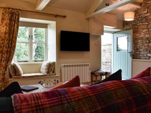 a living room with a couch and a tv on the wall at The Owlery At Aysgarth in Aysgarth