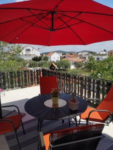 een patio tafel met een rode parasol op een balkon bij Apartments Snježana Carev in Jezera