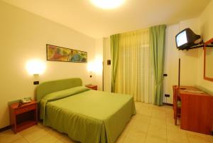 a bedroom with a green bed and a television at Park Hotel & Dependance in Martinsicuro