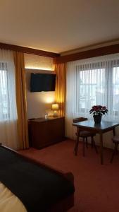ein Hotelzimmer mit einem Schreibtisch und einem Tisch mit Blumen in der Unterkunft Haus Kohl in Semmering