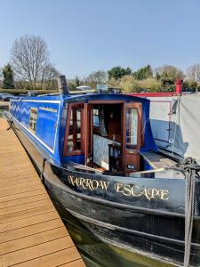 a blue boat is docked next to a dock at Narrow Escape - 50ft Boat on the Grand Union Canal, near Tring in Tring