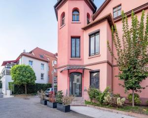 un bâtiment rose avec des plantes devant lui dans l'établissement Le Manoir de Cyrielle - WIFI - 20 min centre ville de Strasbourg, à Bischheim