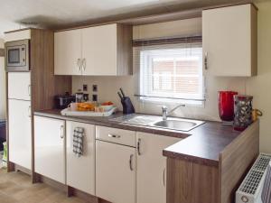 a kitchen with white cabinets and a sink at Bridge End Lodge in Dollar