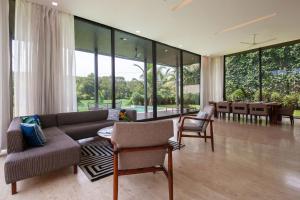 uma sala de estar com um sofá, cadeiras e uma mesa em StayVista at Bella Aquila with Pvt Pool & Lawn - Parra NorthGoa em Anjuna