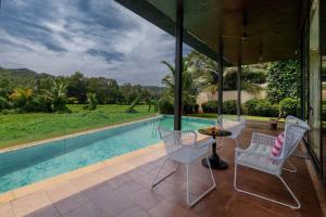 um pátio com uma mesa e cadeiras ao lado de uma piscina em StayVista at Bella Aquila with Pvt Pool & Lawn - Parra NorthGoa em Anjuna