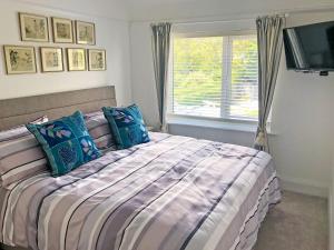 a bedroom with a bed with blue pillows and a window at May Escape in Heswall