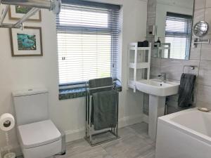 a white bathroom with a toilet and a sink at May Escape in Heswall