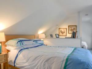 a bedroom with a bed with blue and white sheets at The Hen House At The Old Parsonage in Cote Brook