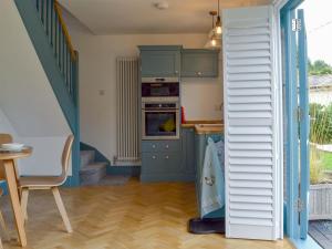 a kitchen with blue cabinets and an oven at The Hen House At The Old Parsonage in Cotebrook