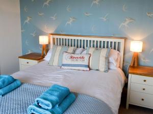 1 dormitorio con 1 cama con 2 lámparas y toallas azules en Gullsway, en Beadnell
