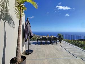 a patio with a table and umbrella and the ocean at Villa Piece of Heaven by LovelyStay in Estreito da Calheta