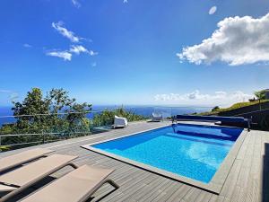 a swimming pool on a deck with chairs and the ocean at Villa Piece of Heaven by LovelyStay in Estreito da Calheta