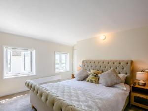 a bedroom with a large bed with two windows at Rose Cottage in Reedham