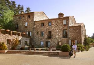 a woman walking a dog in front of a large stone building at Le Domaine de Falgos Golf & Spa in Saint-Laurent-de-Cerdans