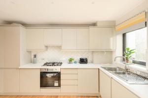 a white kitchen with white cabinets and a sink at Modern Mews Apartment - New Town in Edinburgh
