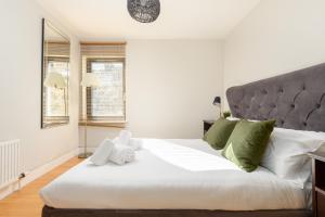 a bedroom with a large white bed with green pillows at Modern Mews Apartment - New Town in Edinburgh