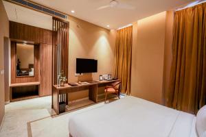 a bedroom with a bed and a desk with a television at Gulab Kothi by Royal Orchid Hotels Limited Varanasi in Varanasi