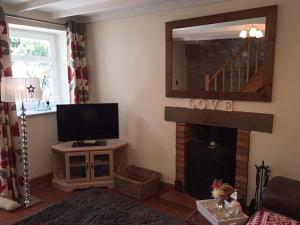a living room with a television and a fireplace at Islas Cottage in Ystradgynlais
