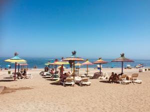 een strand met veel stoelen en parasols en de oceaan bij Casa del Sol, la Paloma beach apartment with pool in Manilva