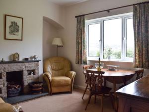 a living room with a table and a chair and a fireplace at Cobbs Cottage in Grosmont