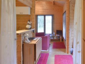 a living room with wooden walls and pink rugs at Gooseberry Lodge in Tollard Royal