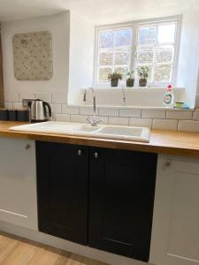 a kitchen counter with a sink and two windows at Cosy two bedrooom cottage set in a Dorset village in Sturminster Newton