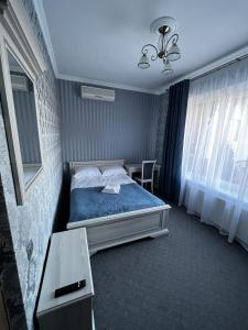 a bedroom with a bed with blue sheets and a window at Zolotoy Fazan in Mykolaiv