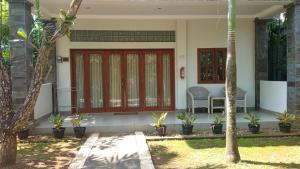 uma casa com uma porta vermelha e uma cadeira num quintal em The Gecho Inn Country em Jepara