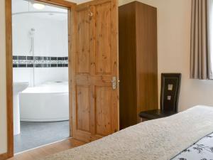 um quarto com uma cama e uma casa de banho com uma banheira em The Pigsty em Llantrisant