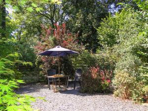 uma mesa e cadeiras sob um guarda-sol num jardim em The Pigsty em Llantrisant