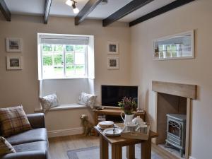 a living room with a fireplace and a tv at Derwent Cottage in Hackness
