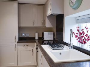 a kitchen with a sink and a microwave at Derwent Cottage in Hackness