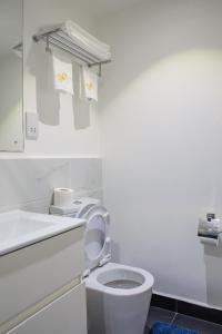 a white bathroom with a toilet and a sink at The Avery, 2 Bed Duplex Apartment at Embassy Gardens in Accra