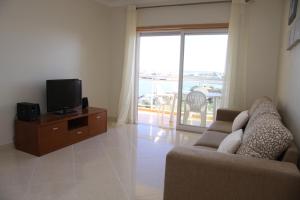 sala de estar con sofá, TV y balcón en Apartamento Arade Portimao, en Portimão