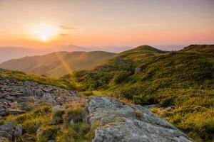 einen Sonnenuntergang in den Bergen mit Felsen im Vordergrund in der Unterkunft Byczy Rog noclehy na hranici in Králíky