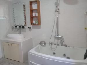 ein weißes Badezimmer mit einer Badewanne und einem Waschbecken in der Unterkunft Hotel SU kataragama in Kataragama