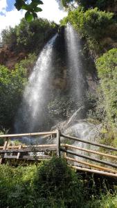 a waterfall on the side of a hill with a fence at Casa El Olmo de Navajas in Navajas +16 photos