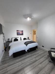 a bedroom with two beds with white walls and wooden floors at Eastend Apartments in London