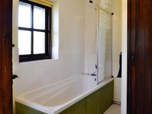 uma banheira branca na casa de banho com uma janela em Buzzard Cottage em Devynock