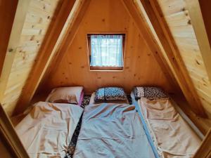 dwa łóżka w małym pokoju w drewnianym domku w obiekcie Prokosko Resort w mieście Fojnica